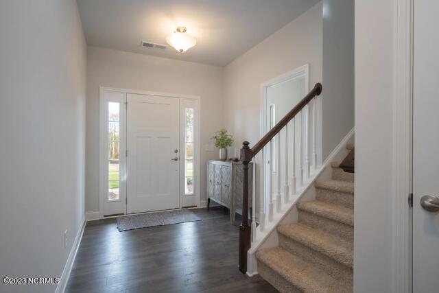 foyer featuring stairs, baseboards, visible vents, and dark wood-type flooring