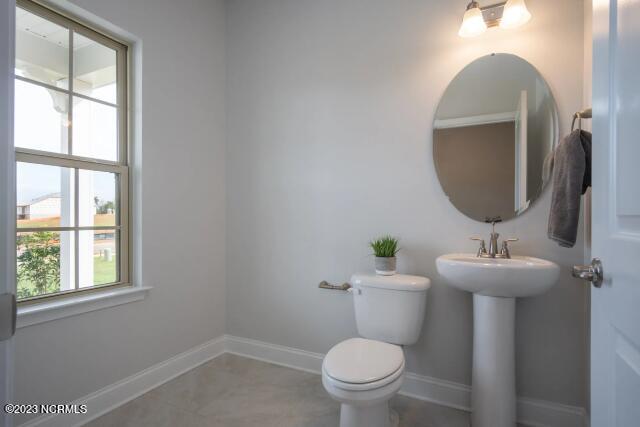 half bathroom with a sink, baseboards, and toilet