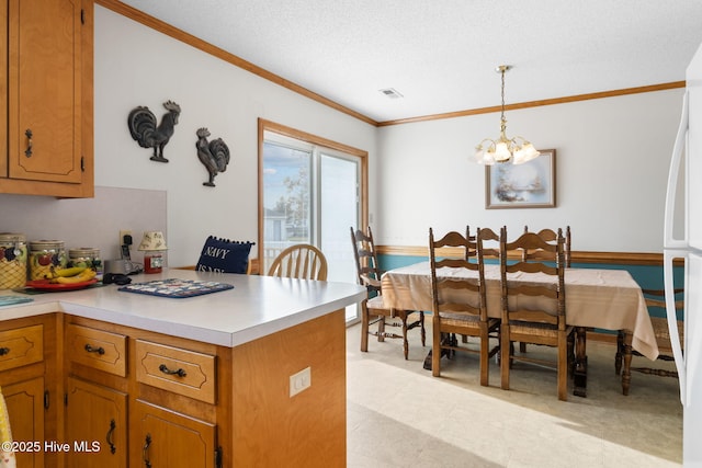 kitchen featuring visible vents, light countertops, ornamental molding, hanging light fixtures, and brown cabinetry