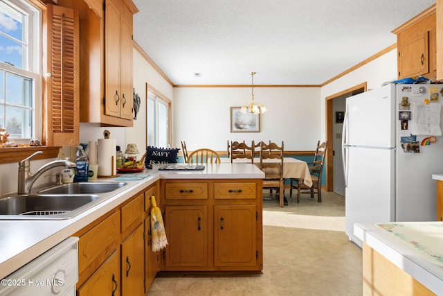 kitchen with white appliances, light countertops, crown molding, pendant lighting, and a sink