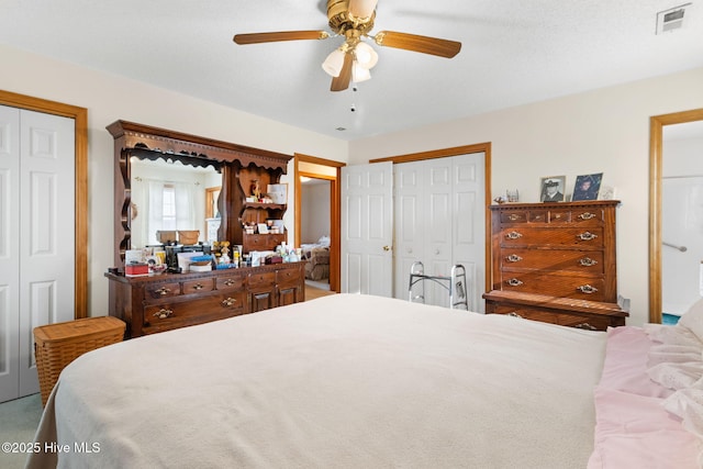 bedroom with a ceiling fan, visible vents, and multiple closets