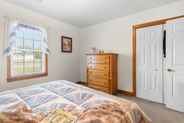 bedroom featuring light carpet, a textured ceiling, baseboards, and a closet