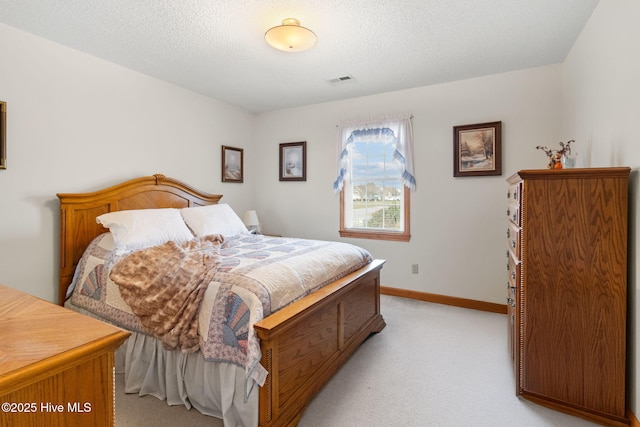 bedroom with light carpet, a textured ceiling, visible vents, and baseboards