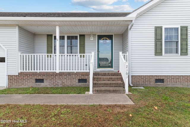 view of exterior entry featuring crawl space, covered porch, and a yard