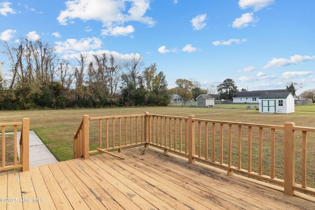 wooden terrace featuring a shed, a lawn, and an outdoor structure