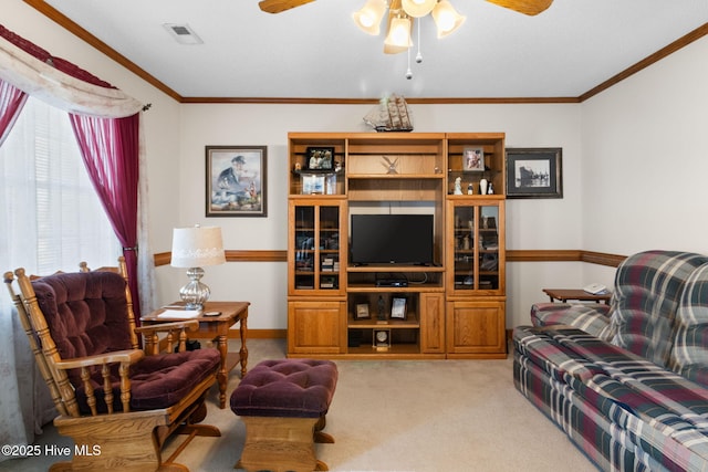 living area featuring light colored carpet, a ceiling fan, baseboards, visible vents, and ornamental molding