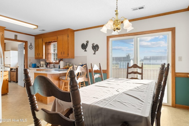 dining space with plenty of natural light, visible vents, a chandelier, and crown molding