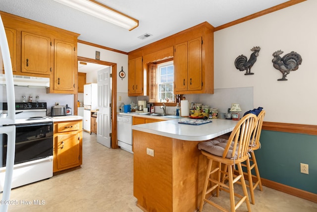 kitchen featuring brown cabinets, visible vents, light countertops, white appliances, and a peninsula