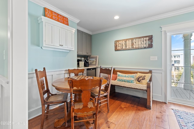 dining space with recessed lighting, ornamental molding, light wood-style floors, wainscoting, and a decorative wall