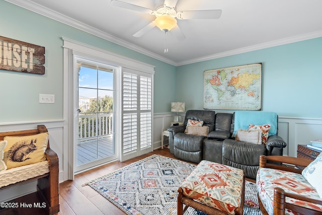 living area featuring a wainscoted wall, wood finished floors, and ornamental molding