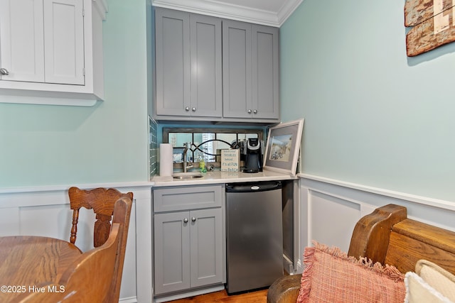 bar featuring a sink, refrigerator, wainscoting, and crown molding