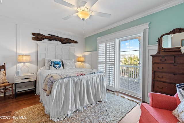 bedroom with a decorative wall, wood finished floors, ornamental molding, and access to outside