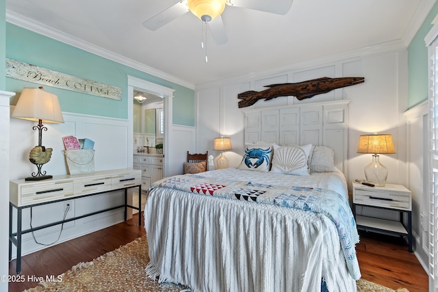 bedroom with a ceiling fan, wood finished floors, ensuite bathroom, crown molding, and a decorative wall