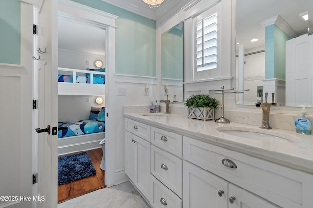 bathroom with double vanity, ensuite bathroom, crown molding, and a sink