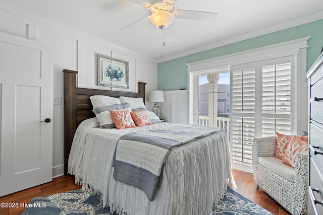 bedroom featuring ornamental molding, a ceiling fan, wood finished floors, a decorative wall, and access to exterior