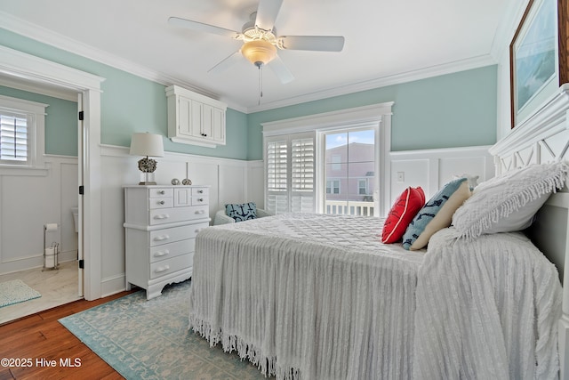 bedroom featuring a wainscoted wall, ornamental molding, a ceiling fan, and wood finished floors