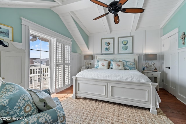 bedroom featuring access to outside, wood finished floors, a decorative wall, ceiling fan, and vaulted ceiling with beams