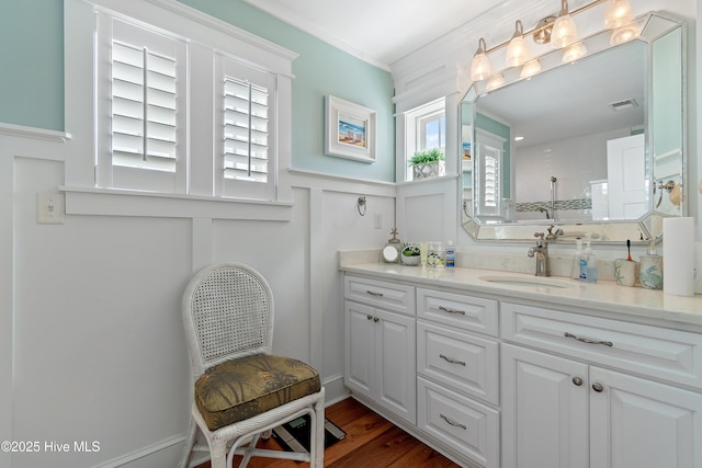 bathroom with visible vents, wood finished floors, a decorative wall, walk in shower, and vanity