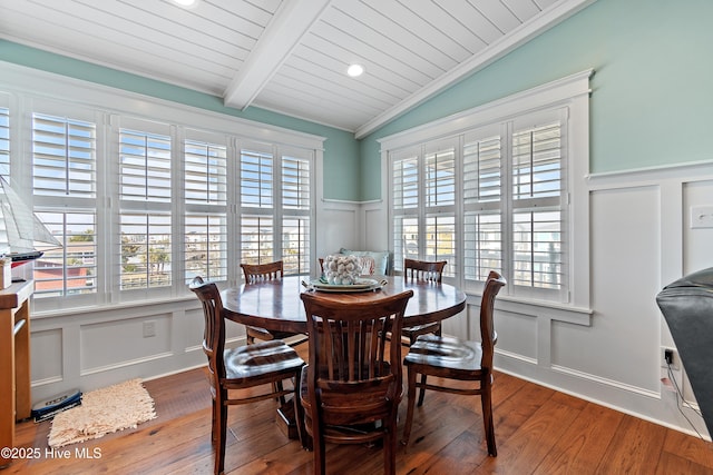 dining room with lofted ceiling with beams, ornamental molding, wood-type flooring, wooden ceiling, and a decorative wall