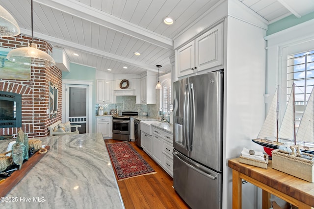 kitchen featuring light stone counters, stainless steel appliances, backsplash, and white cabinets