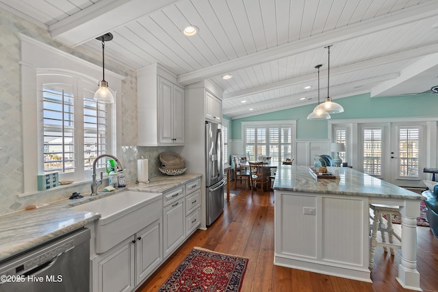 kitchen with lofted ceiling with beams, hardwood / wood-style floors, a wealth of natural light, appliances with stainless steel finishes, and a sink