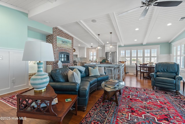 living area featuring a wainscoted wall, dark wood-style flooring, a wealth of natural light, and ceiling fan