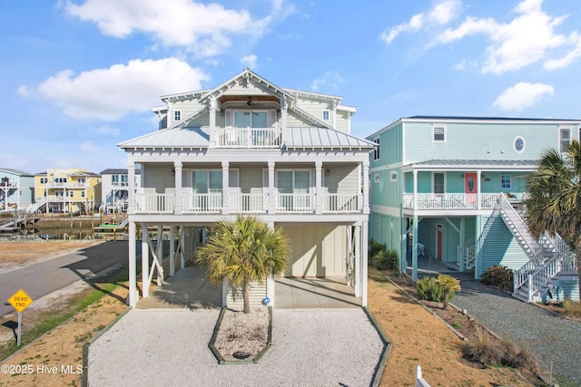 coastal home featuring metal roof, a balcony, a carport, driveway, and a standing seam roof