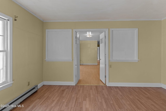 empty room with a healthy amount of sunlight, light wood-style floors, a baseboard heating unit, and crown molding