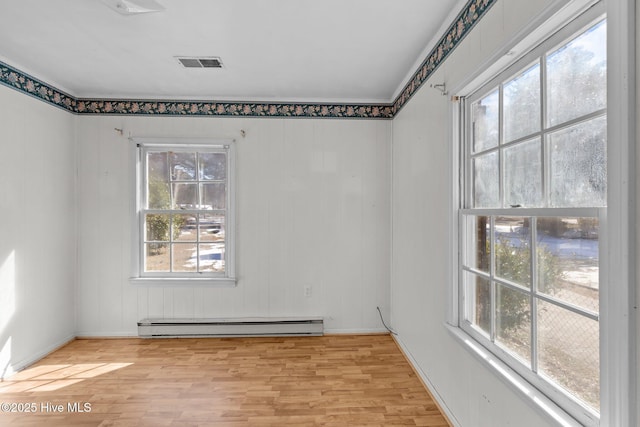 spare room with a baseboard heating unit, visible vents, and light wood-style floors