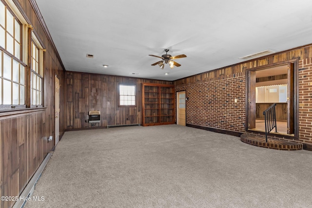 spare room featuring brick wall, heating unit, baseboard heating, carpet floors, and wood walls