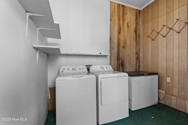 clothes washing area with laundry area, wooden walls, separate washer and dryer, and dark colored carpet