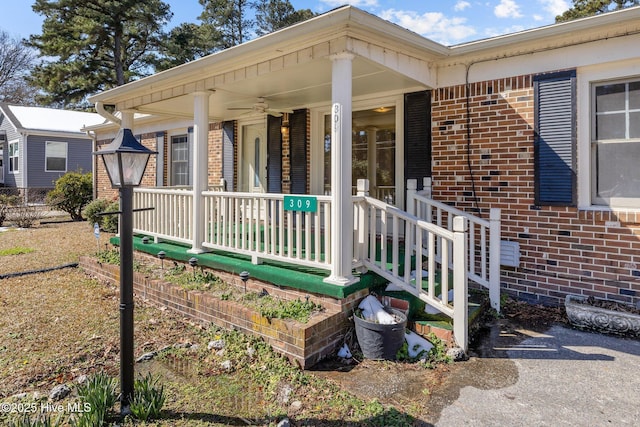 entrance to property with a porch and brick siding