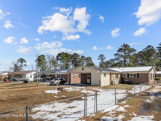 ranch-style home featuring a carport, brick siding, driveway, and a fenced front yard