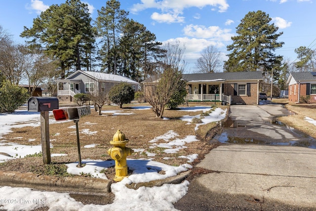 single story home with driveway, a porch, and brick siding