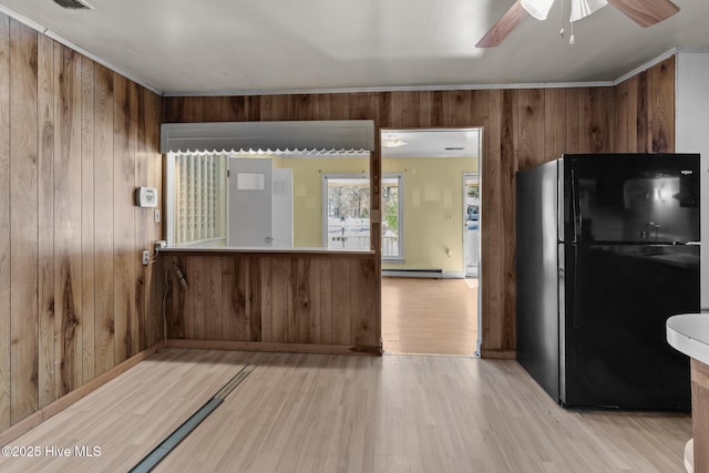 kitchen with light wood-style floors, freestanding refrigerator, a baseboard heating unit, ceiling fan, and wood walls