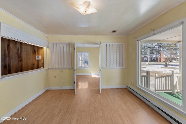 unfurnished room with baseboards, visible vents, light wood-style flooring, and baseboard heating