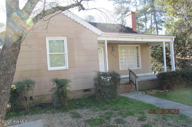 view of front of home with crawl space, covered porch, and a chimney