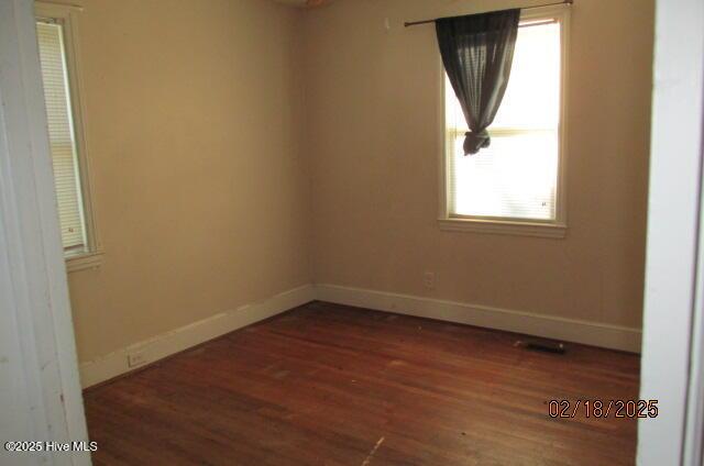 unfurnished room with dark wood-style flooring and baseboards