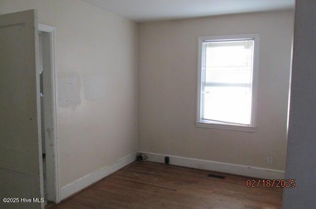 spare room with dark wood-type flooring and baseboards