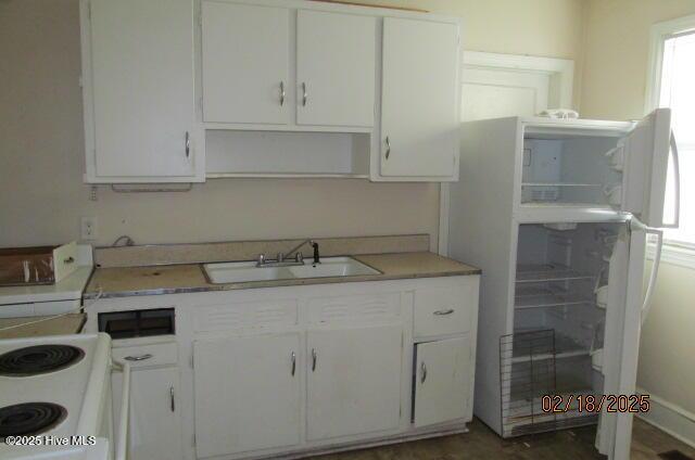 kitchen with light countertops, white appliances, white cabinetry, and a sink