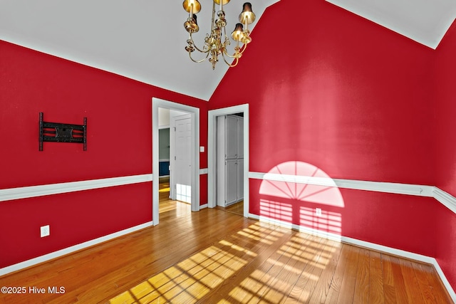 interior space with high vaulted ceiling, wood finished floors, baseboards, and an inviting chandelier