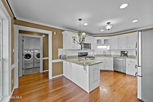 kitchen with light wood-style flooring, a peninsula, white cabinetry, appliances with stainless steel finishes, and washer and clothes dryer