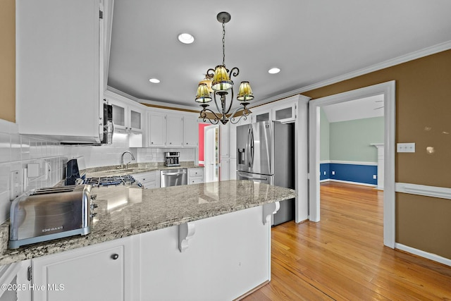 kitchen featuring stainless steel appliances, glass insert cabinets, ornamental molding, white cabinetry, and a peninsula