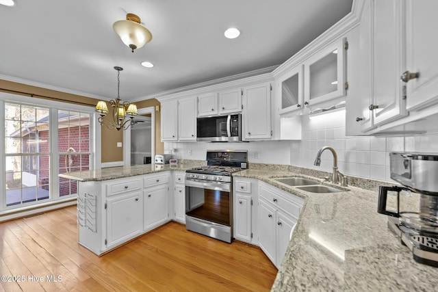 kitchen with stainless steel appliances, white cabinets, a sink, and a peninsula