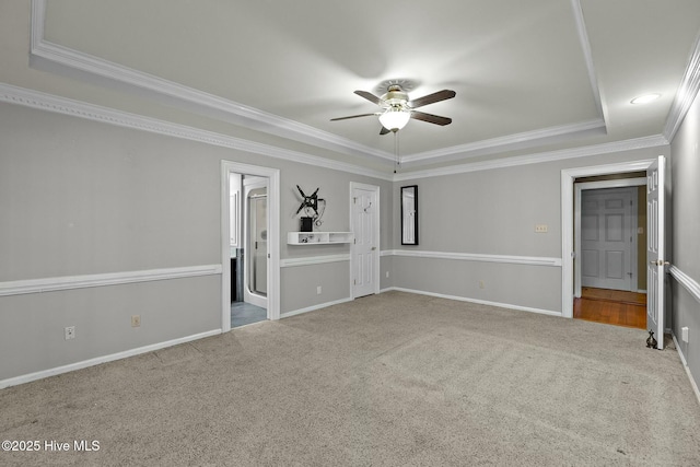 interior space with ensuite bathroom, carpet floors, baseboards, a tray ceiling, and crown molding