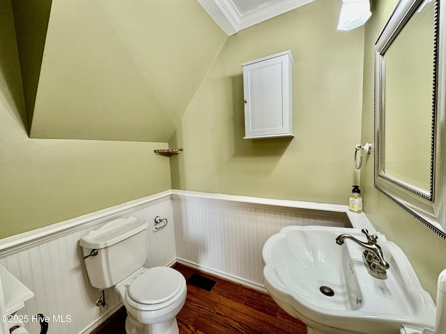 bathroom with vaulted ceiling, a wainscoted wall, a sink, and toilet