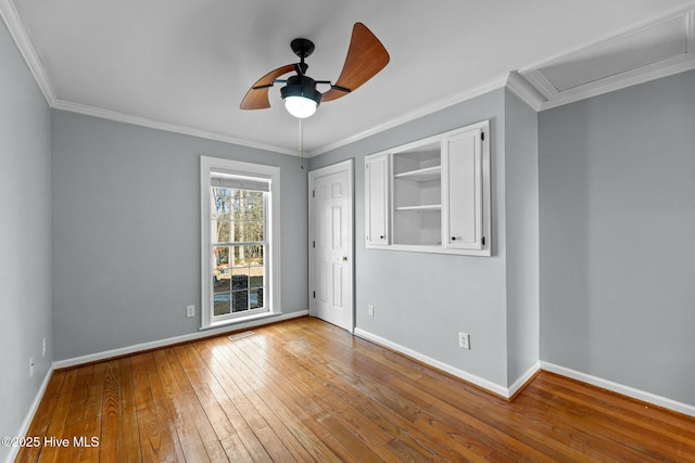 unfurnished room with a ceiling fan, baseboards, crown molding, and hardwood / wood-style floors