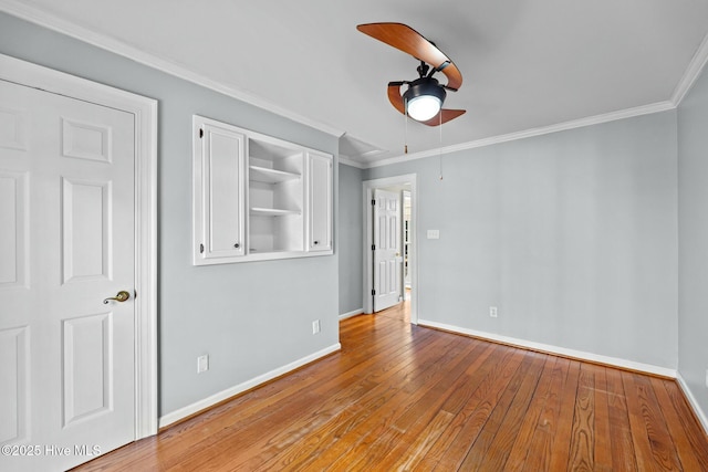 empty room with light wood-type flooring, a ceiling fan, baseboards, and crown molding