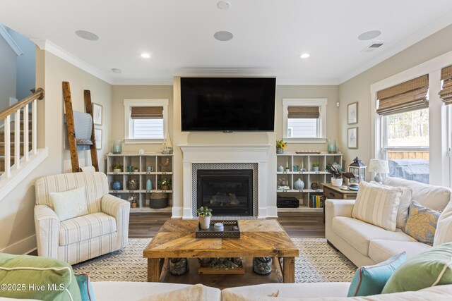 living area with a healthy amount of sunlight, crown molding, stairs, and wood finished floors