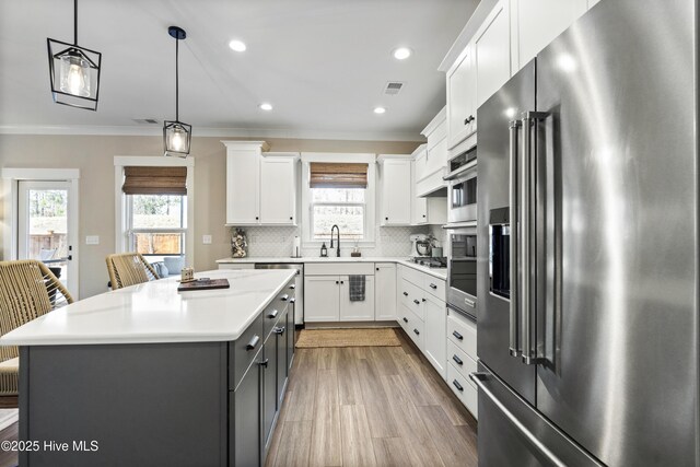 kitchen with stainless steel appliances, a kitchen island, light countertops, and white cabinetry